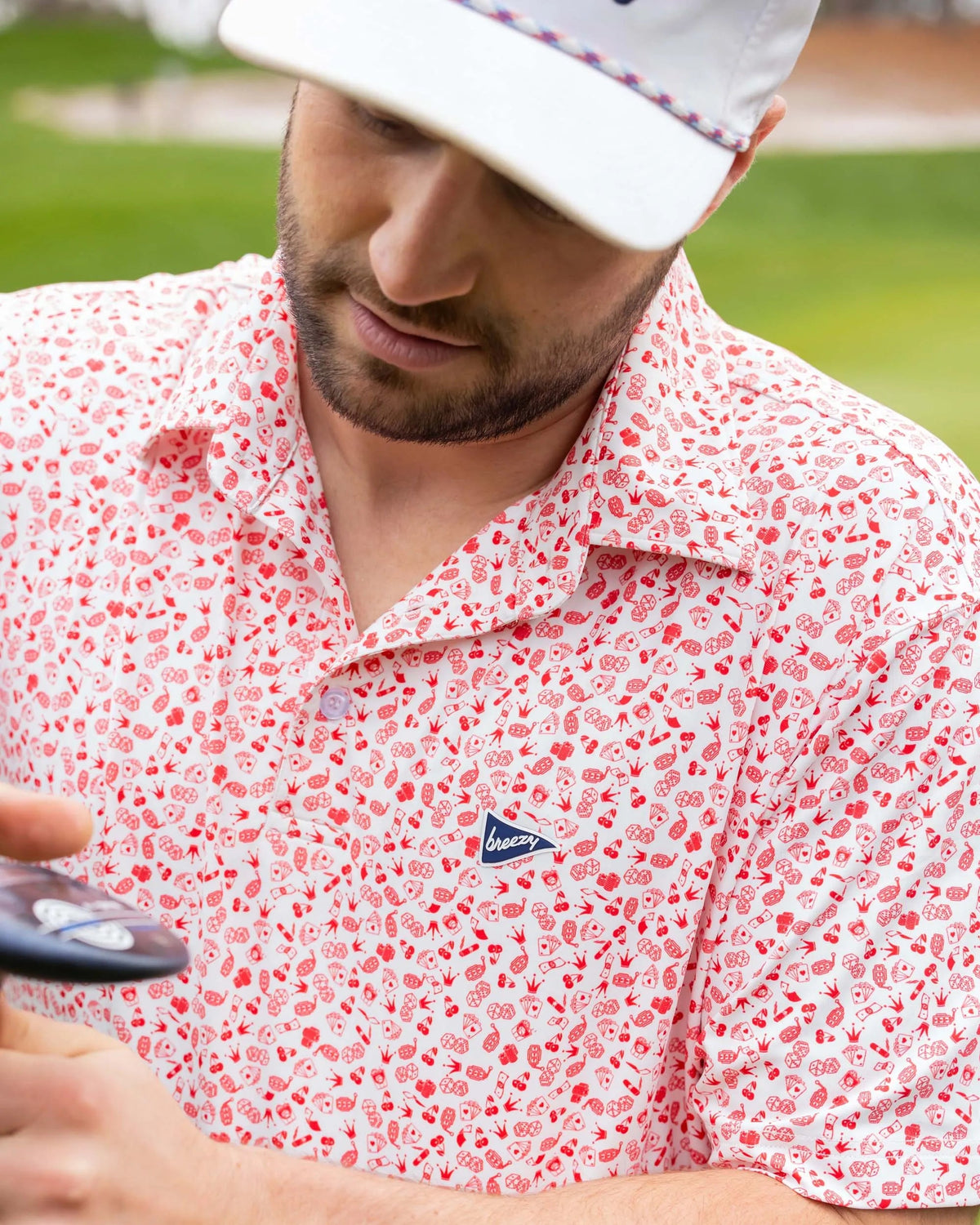 Close-up of Breezy Golf Vegas Baby Polo showing red casino-inspired print and chest logo.