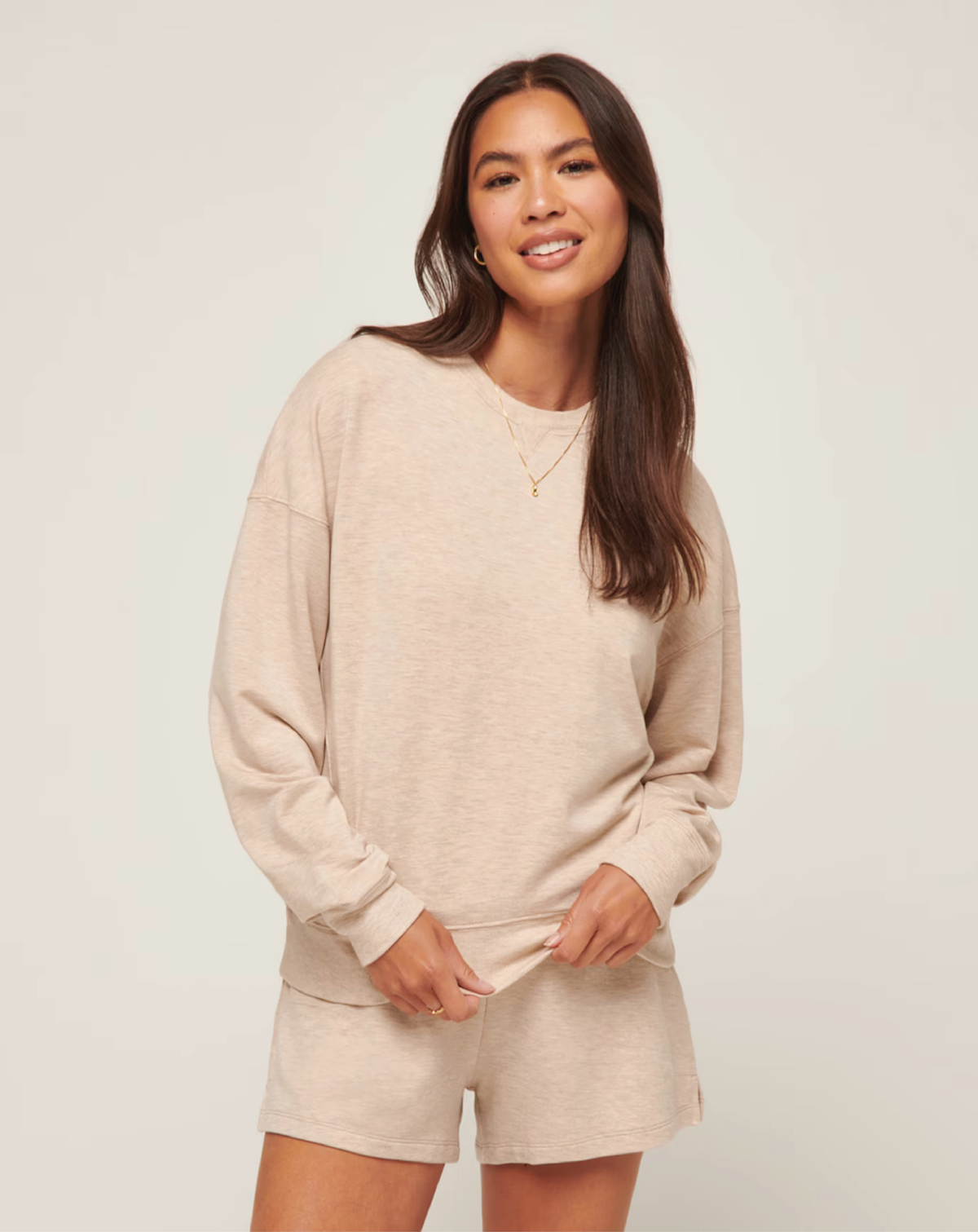 A woman wearing a black long-sleeve crewneck pullover with ribbed details, paired with black pants.