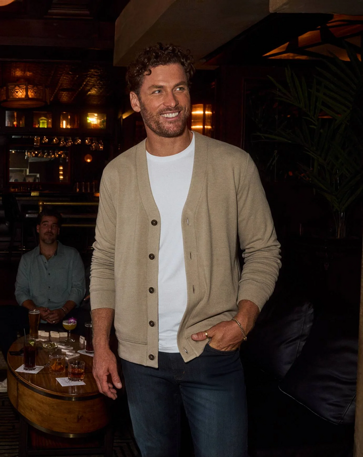 Men’s heather beige cardigan sweater worn casually in a lounge setting with button front and relaxed fit
