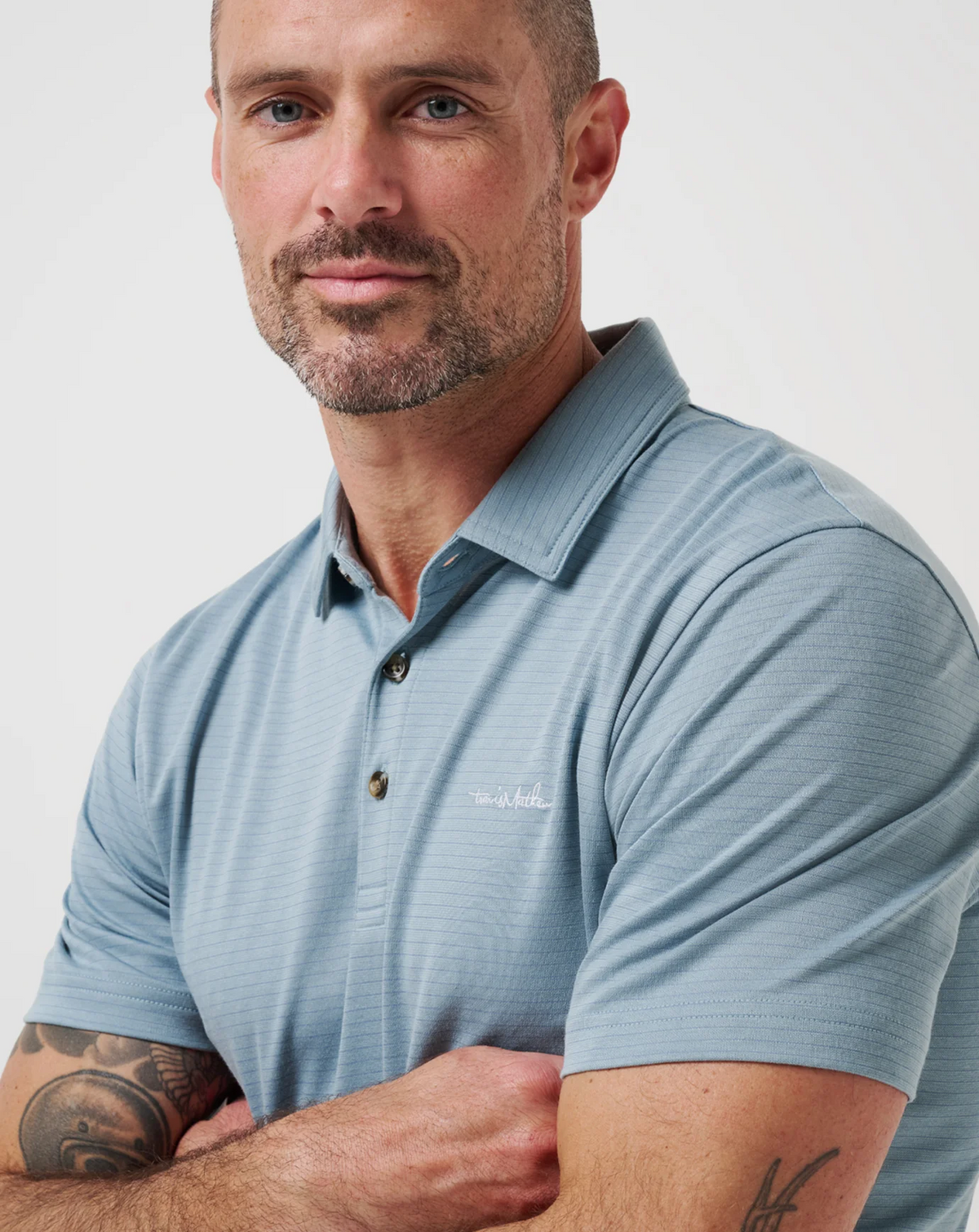 Close-up of model wearing Zinna 2.0 polo in light blue, highlighting collar structure and fabric texture