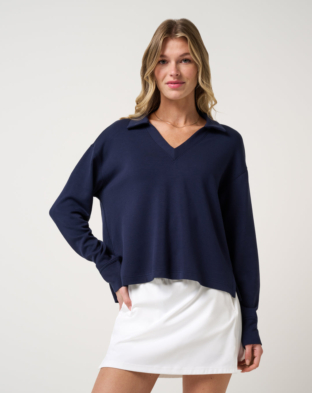 TravisMathew Women's Skyloft Soft V-Neck Pullover in navy worn with white golf skirt front view
