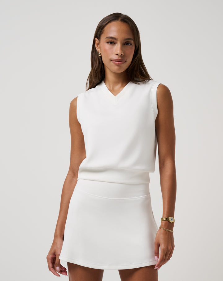 TravisMathew women’s Skyloft Soft Vest in white styled with white golf skirt.