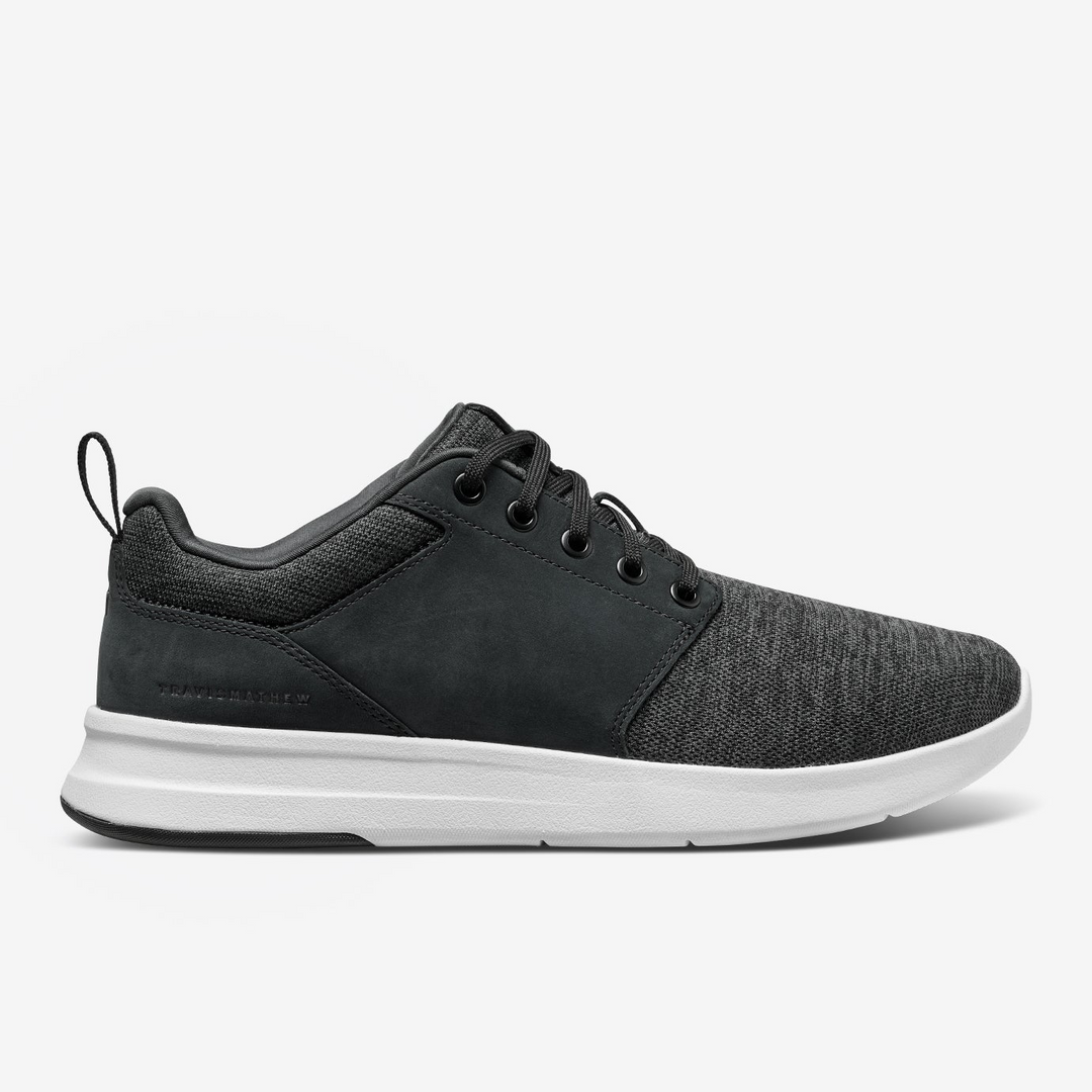 Side view of TravisMathew Daily 3 shoe with knit upper and white cushioned sole.