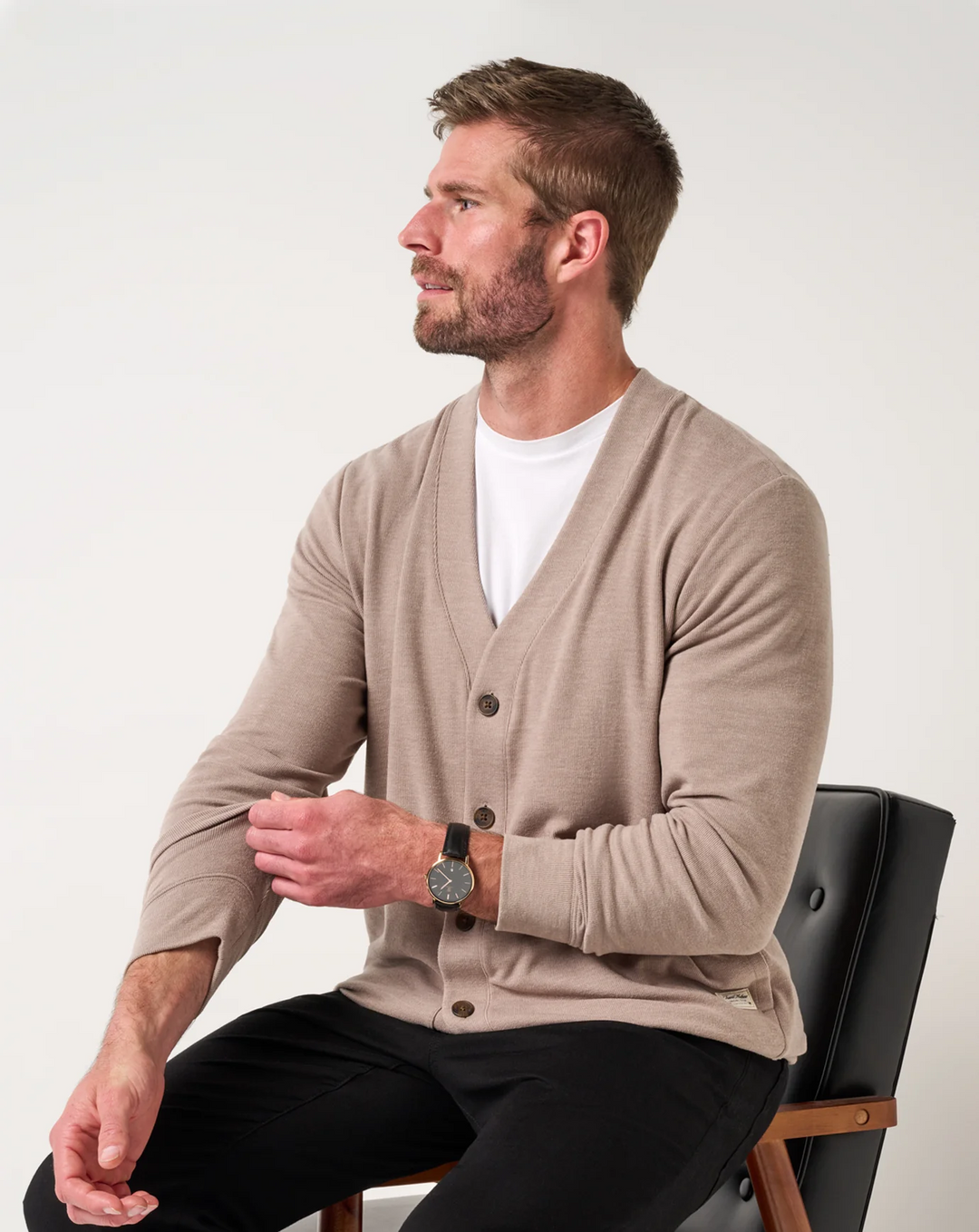 Men wearing a heather beige cardigan sweater seated, showing relaxed fit and button front