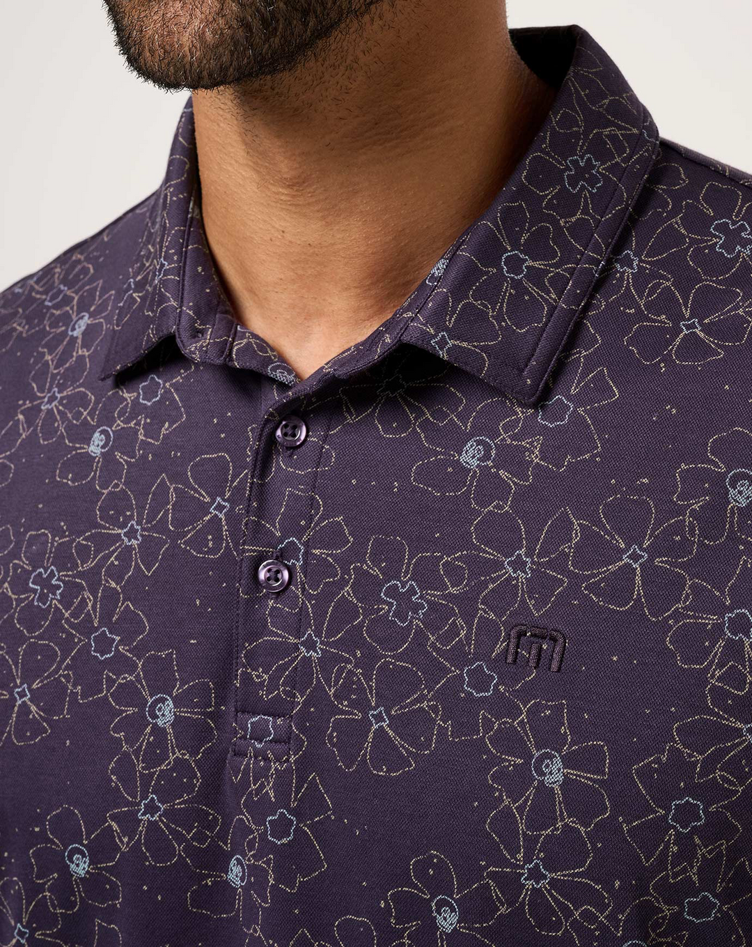 Close-up of TravisMathew Just My Type Polo collar and button placket with floral line print