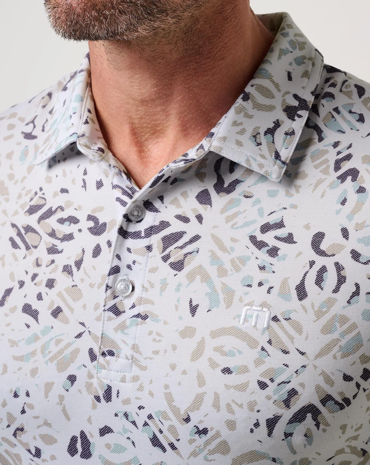 lose-up of TravisMathew Featherweight Chill Polo collar, buttons, and subtle logo detail