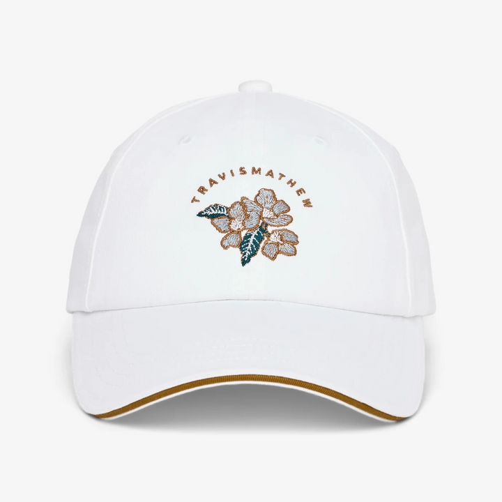 White TravisMathew cap with embroidered floral logo and curved brim