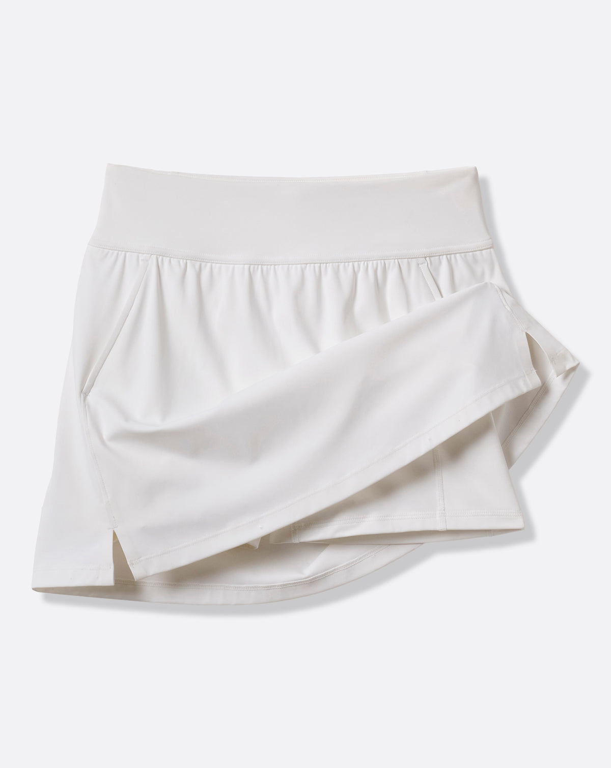 TravisMathew Moveknit Game Set Match Skort in white, angled product view showing the bonded construction and side slit