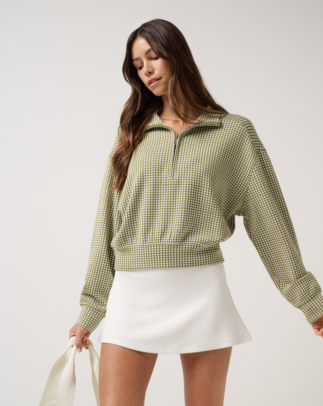 TravisMathew women’s Printed Skyloft Soft Echo half zip pullover styled with white golf skirt for modern golf apparel look.