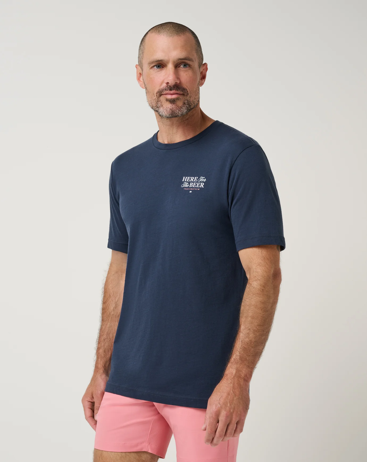 TravisMathew Stout Standard Tee in navy, front angle view on model showing the relaxed fit and scooped hemline